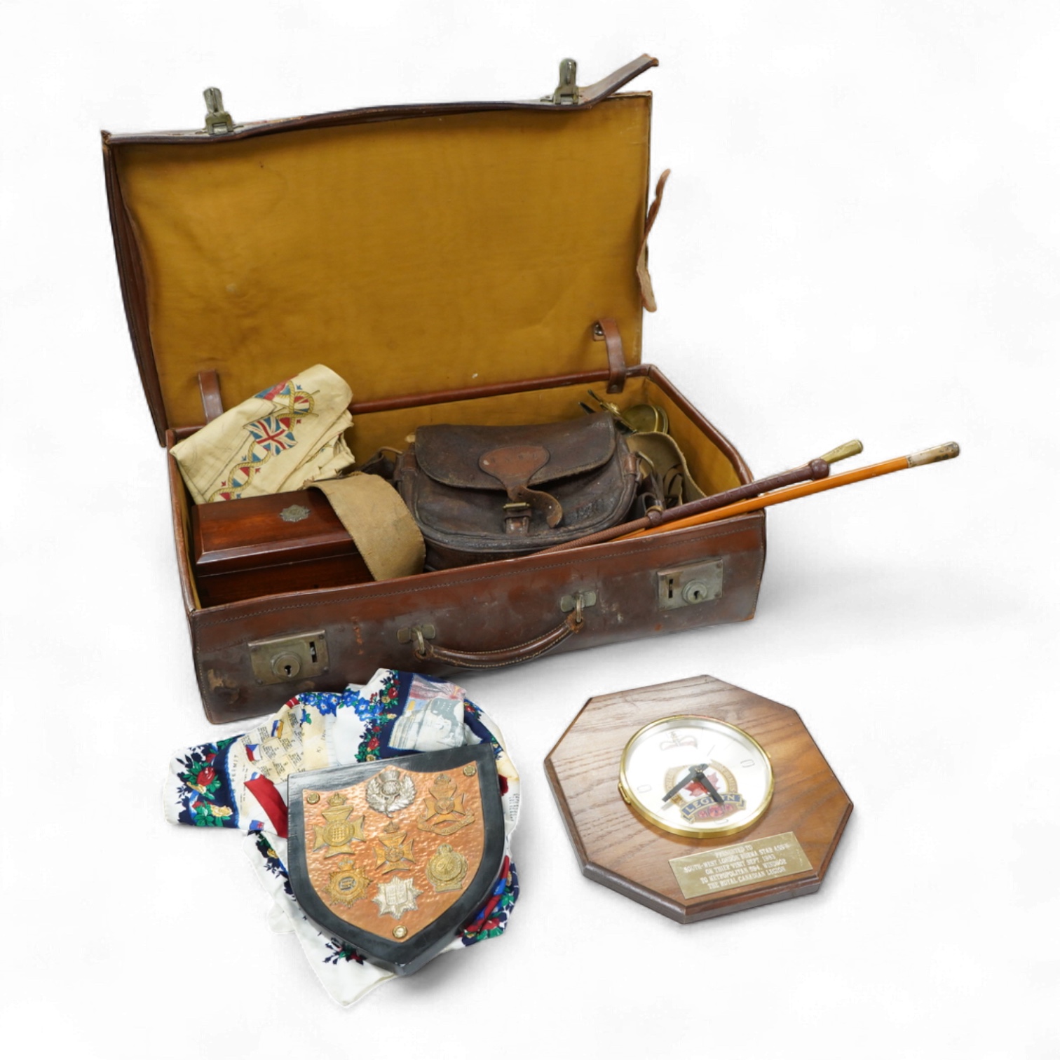 A suitcase of military related items, including; a Manchester Guardian issued early 20th century map of Europe printed on cotton, a First World War trench art match holder the base formed from a cartridge case, two swagg